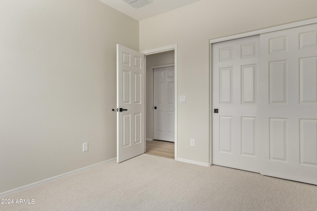 unfurnished bedroom featuring light carpet and a closet