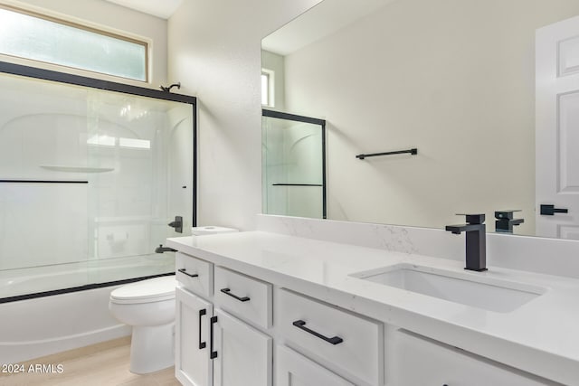 full bathroom with shower / bath combination with glass door, vanity, toilet, and hardwood / wood-style flooring