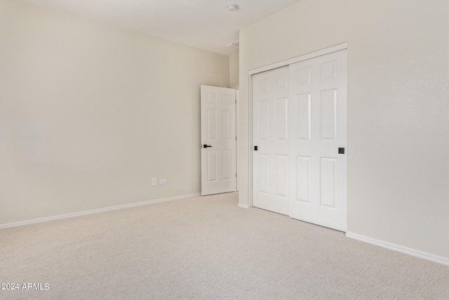 unfurnished bedroom featuring light colored carpet and a closet