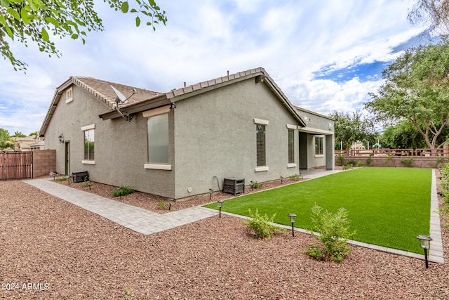 rear view of property with cooling unit and a lawn