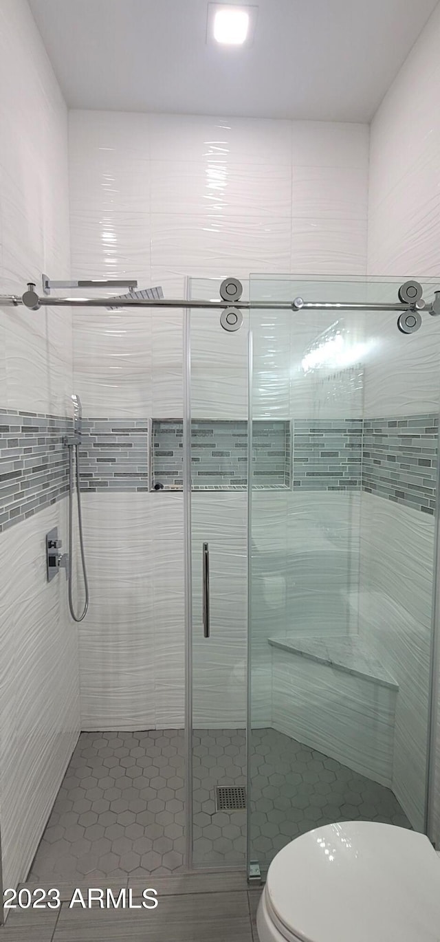 bathroom featuring an enclosed shower, toilet, and tile walls