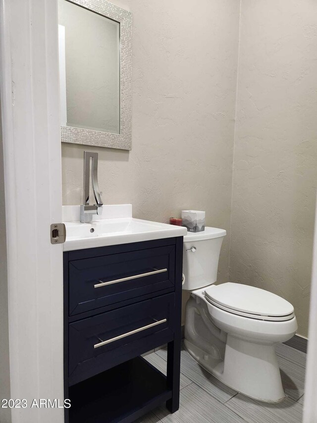 bathroom featuring tile flooring, toilet, and vanity