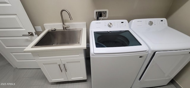 laundry room with light tile floors, washing machine and dryer, cabinets, and sink