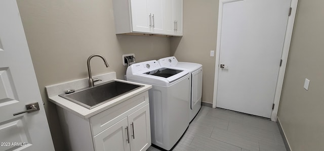 laundry room featuring cabinets, sink, light tile floors, hookup for a washing machine, and washing machine and clothes dryer