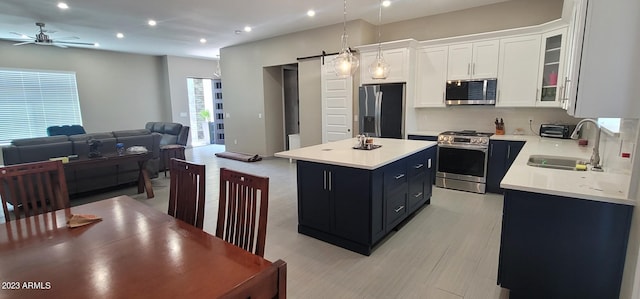 kitchen with decorative light fixtures, ceiling fan, a barn door, stainless steel appliances, and a kitchen island