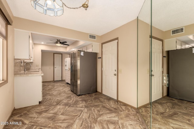 kitchen featuring ceiling fan, stainless steel refrigerator with ice dispenser, sink, and white cabinetry