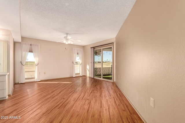 unfurnished room with ceiling fan, light wood-type flooring, and a textured ceiling