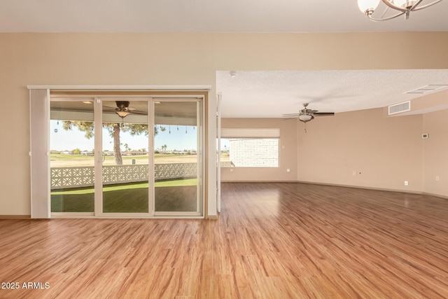 unfurnished room featuring light wood-type flooring, a chandelier, and a textured ceiling