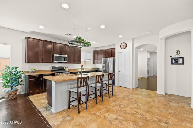 3022 E Santa Fe Ln, Gilbert, AZ 85297 - kitchen featuring appliances with stainless steel finishes, arched walkways, a breakfast bar area, an island with sink, and recessed lighting