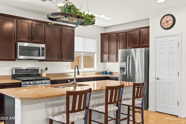 3022 E Santa Fe Ln, Gilbert, AZ 85297 - kitchen featuring appliances with stainless steel finishes, dark brown cabinetry, light stone counters, a kitchen breakfast bar, and recessed lighting