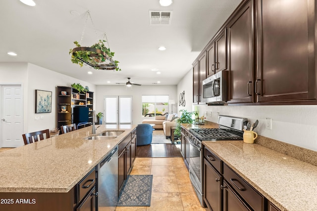 3022 E Santa Fe Ln, Gilbert, AZ 85297 - kitchen with stainless steel appliances, a ceiling fan, recessed lighting, dark brown cabinets, and a center island with sink