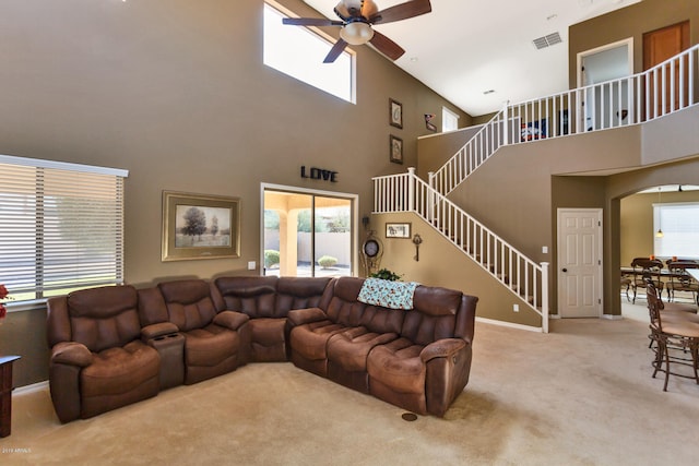 carpeted living room featuring ceiling fan and a high ceiling