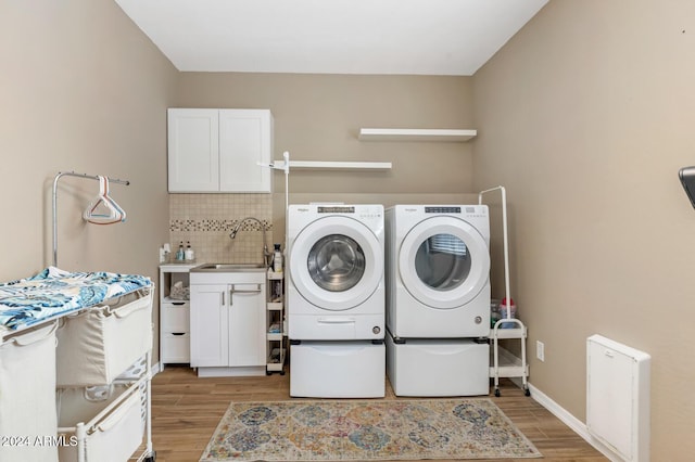 laundry area with cabinet space, separate washer and dryer, light wood-style flooring, and baseboards