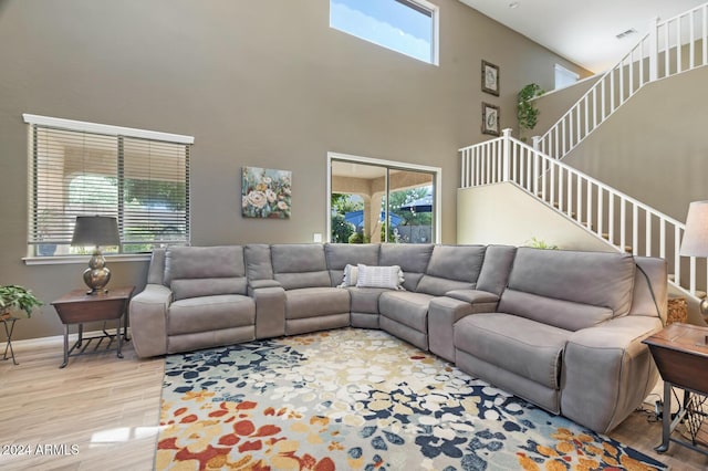 living area featuring plenty of natural light, a high ceiling, wood finished floors, stairway, and baseboards