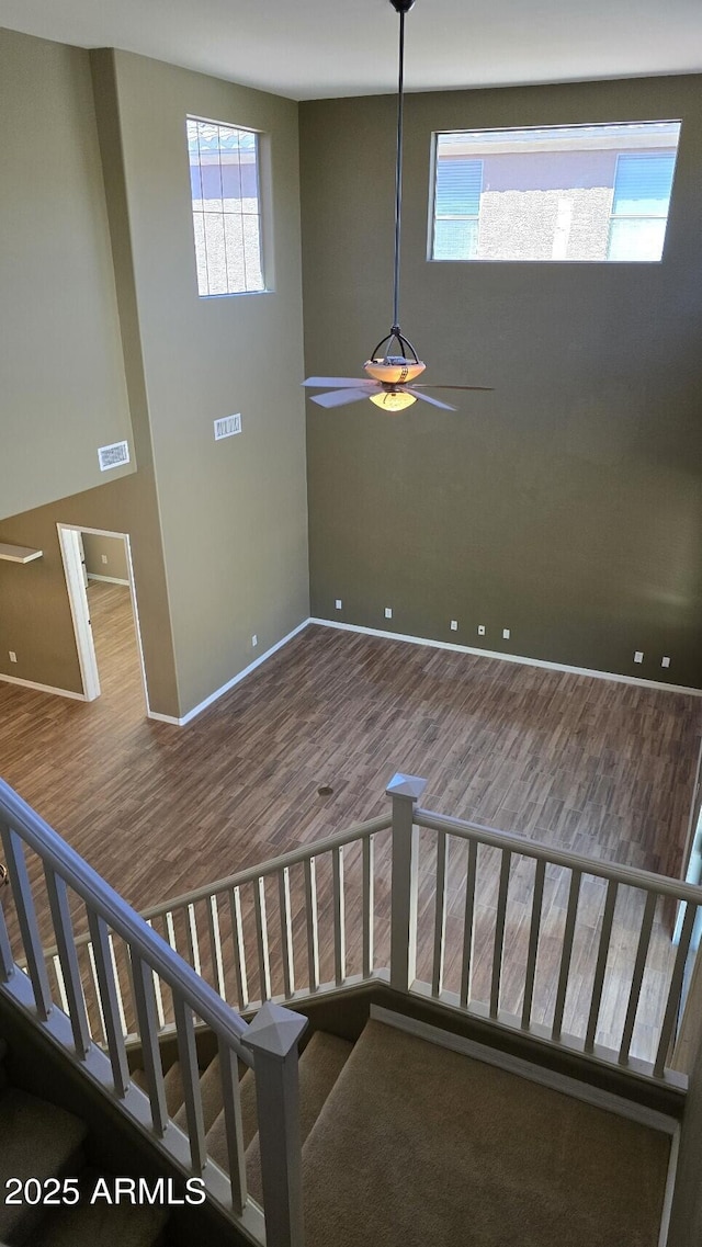 staircase featuring wood finished floors, baseboards, and a ceiling fan