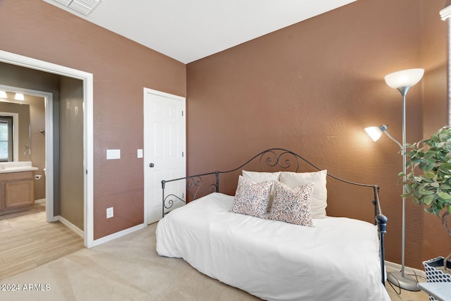 bedroom featuring connected bathroom and light wood-type flooring