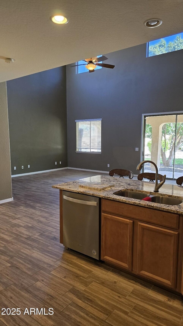 kitchen featuring dishwasher, a sink, open floor plan, light stone counters, and recessed lighting