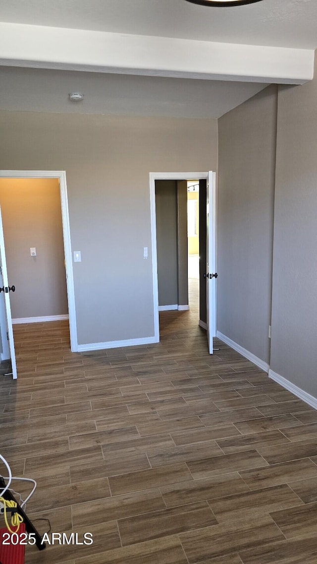 unfurnished room with baseboards and dark wood-style floors