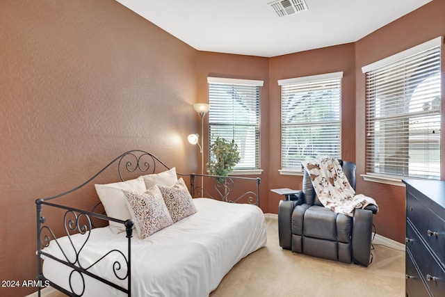bedroom with light carpet, baseboards, and a textured wall