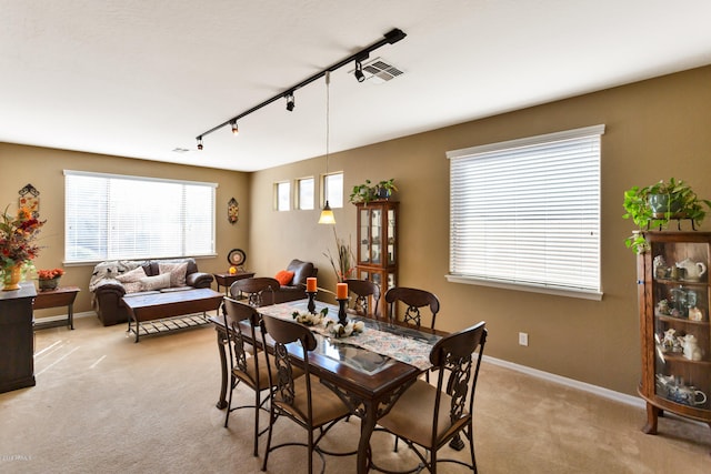 carpeted dining area featuring a healthy amount of sunlight and rail lighting