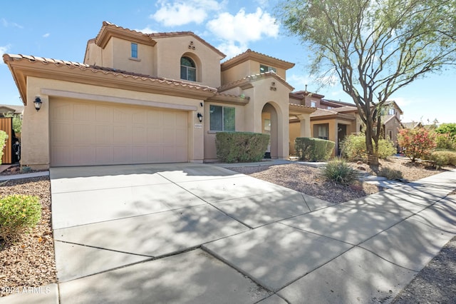 mediterranean / spanish-style house with stucco siding, driveway, an attached garage, and a tile roof