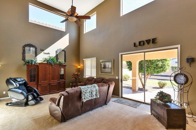 carpeted living room with a towering ceiling, plenty of natural light, and ceiling fan