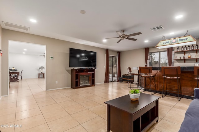 tiled living room featuring ceiling fan and indoor bar