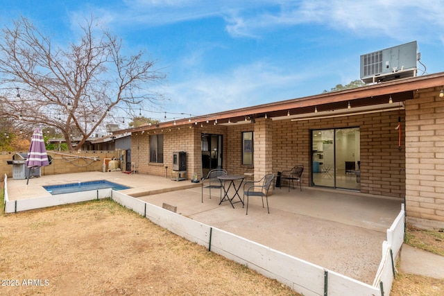 rear view of house featuring a fenced in pool, cooling unit, and a patio area