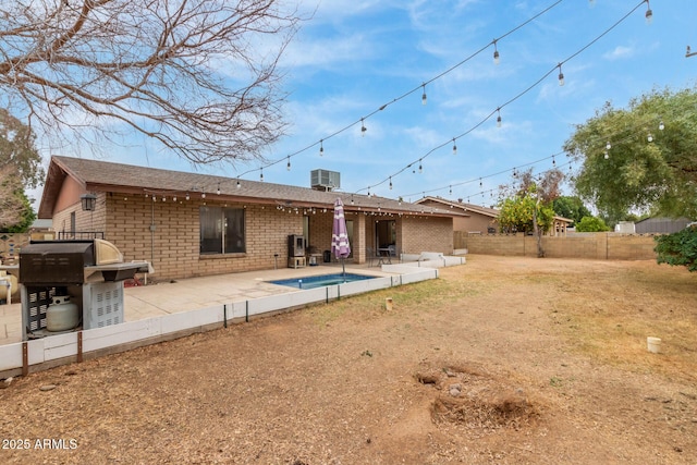 rear view of property with a fenced in pool, central AC unit, and a patio area