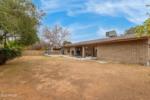 rear view of property with cooling unit, a yard, and a patio