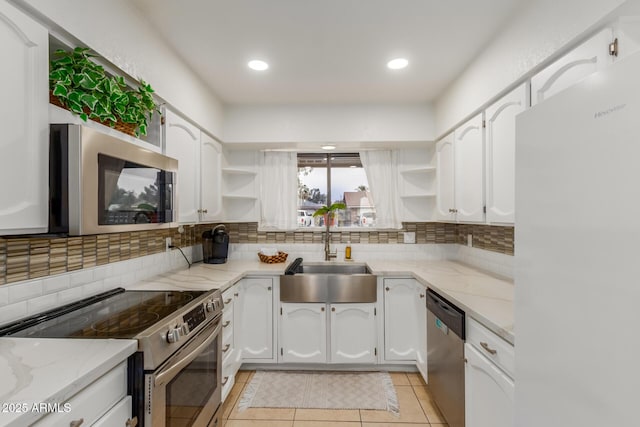 kitchen with sink, backsplash, white cabinets, light stone counters, and stainless steel appliances