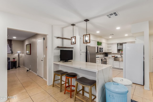 kitchen with white cabinetry, appliances with stainless steel finishes, kitchen peninsula, and light tile patterned floors