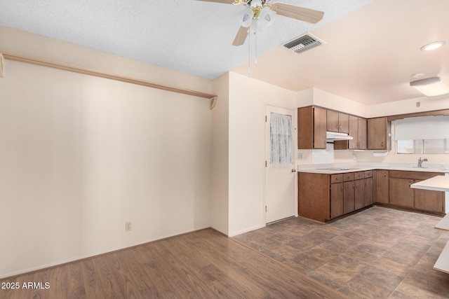 kitchen with visible vents, electric stovetop, light countertops, under cabinet range hood, and a sink