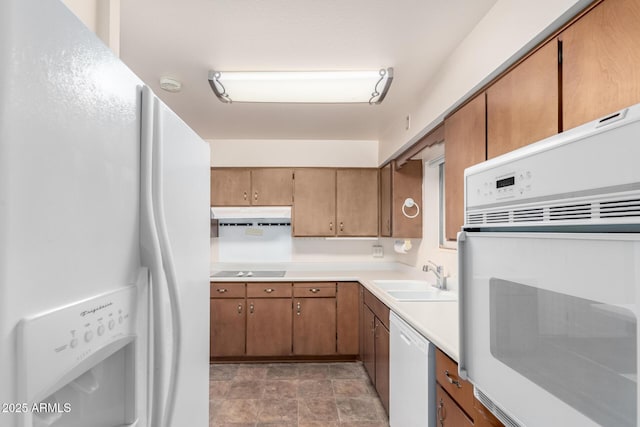 kitchen featuring brown cabinets, light countertops, a sink, white appliances, and under cabinet range hood