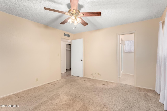 unfurnished bedroom featuring a textured ceiling, ceiling fan, visible vents, carpet, and ensuite bath