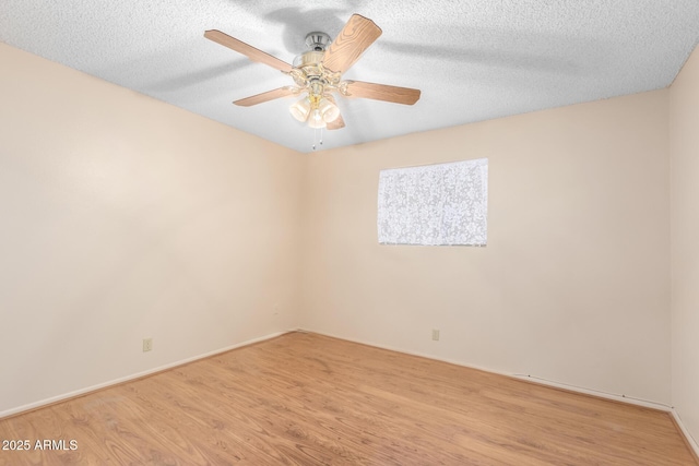 spare room featuring baseboards, ceiling fan, light wood-style flooring, and a textured ceiling