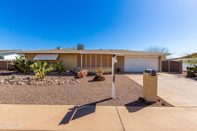 ranch-style house featuring a garage, brick siding, driveway, and fence