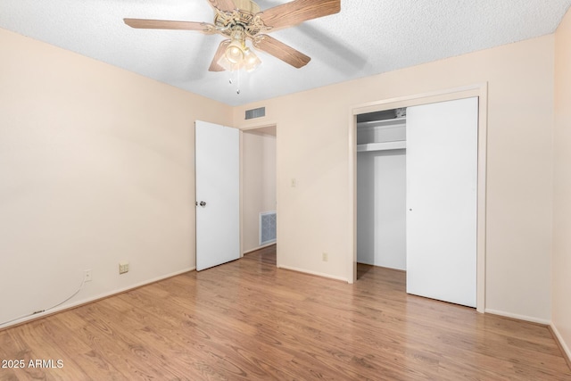 unfurnished bedroom with a textured ceiling, visible vents, and wood finished floors