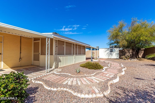 view of yard featuring a storage unit, an outdoor structure, fence, and a sunroom