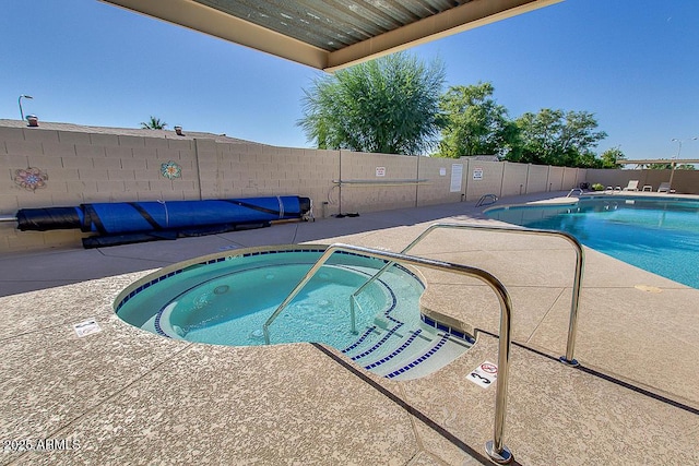 pool featuring a community hot tub, a patio, and fence