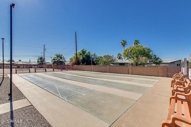 view of community with shuffleboard and fence