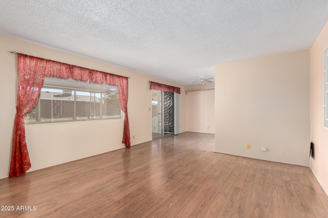 empty room with a textured ceiling, wood finished floors, and a ceiling fan