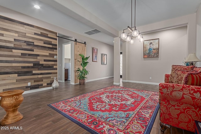 sitting room with dark hardwood / wood-style flooring, wood walls, and a barn door