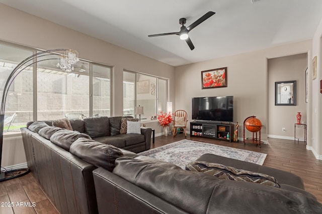 living room featuring dark wood-type flooring and ceiling fan with notable chandelier