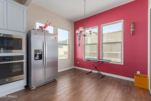 kitchen featuring a wealth of natural light, appliances with stainless steel finishes, white cabinetry, and hanging light fixtures