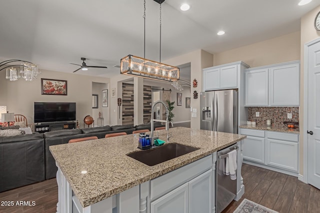 kitchen featuring white cabinetry, an island with sink, stainless steel appliances, ceiling fan with notable chandelier, and sink