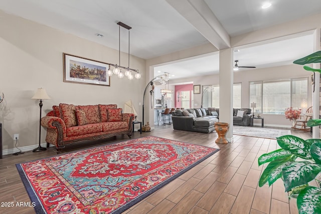 living room featuring beam ceiling and ceiling fan with notable chandelier