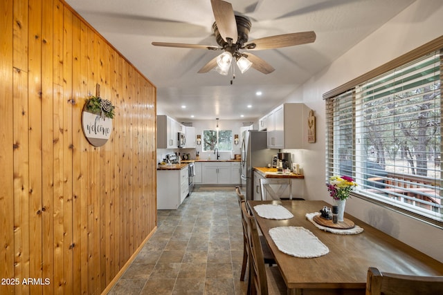 dining space with wood walls, recessed lighting, and a ceiling fan