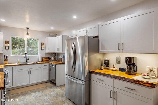 kitchen with butcher block countertops, a sink, stainless steel appliances, and recessed lighting