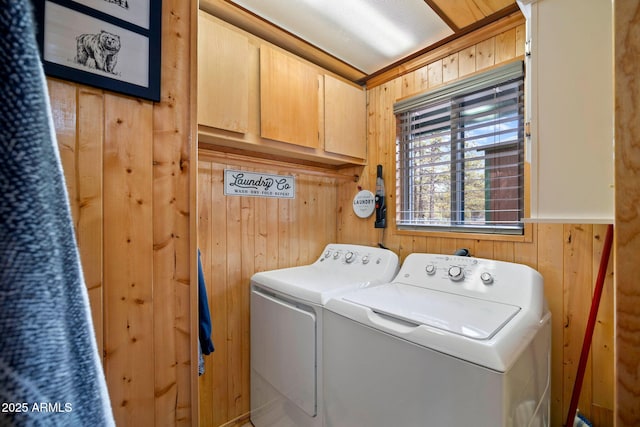 washroom featuring a wainscoted wall, cabinet space, wood walls, and washer and dryer